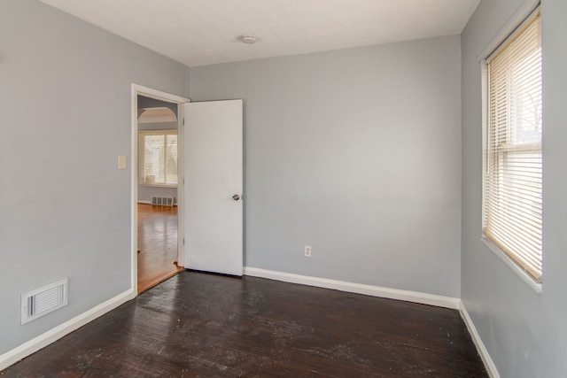 unfurnished room featuring a healthy amount of sunlight and dark hardwood / wood-style floors