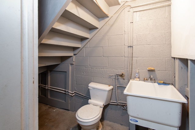 bathroom featuring toilet, concrete flooring, and sink