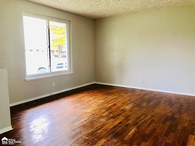 empty room featuring dark hardwood / wood-style flooring, a healthy amount of sunlight, and a textured ceiling