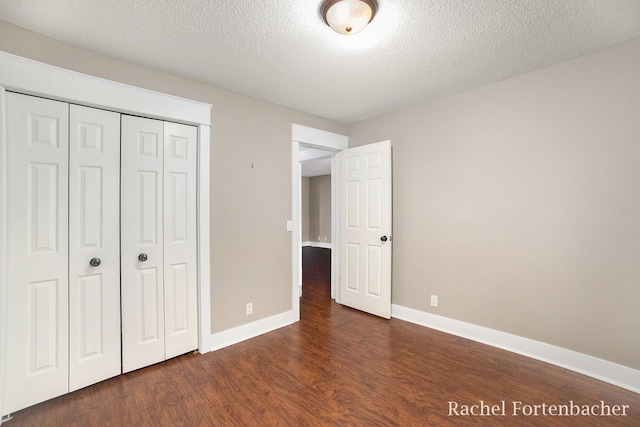 unfurnished bedroom with dark hardwood / wood-style floors, a textured ceiling, and a closet