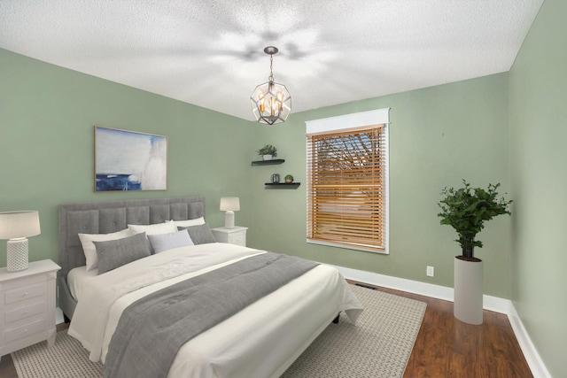 bedroom featuring dark wood-type flooring, a textured ceiling, and a notable chandelier