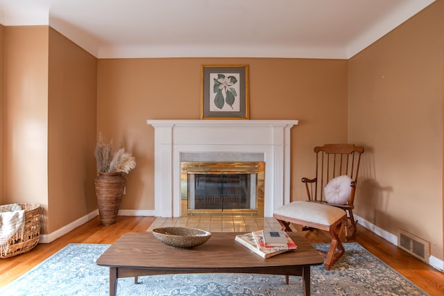 sitting room featuring a tiled fireplace and hardwood / wood-style flooring