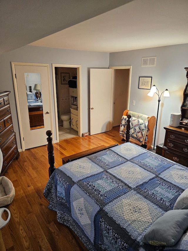 bedroom featuring ensuite bath and hardwood / wood-style floors