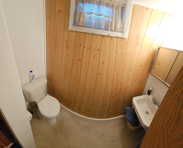 bathroom with wooden walls, sink, and toilet