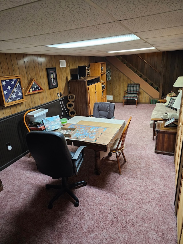 home office featuring carpet, a drop ceiling, and wood walls