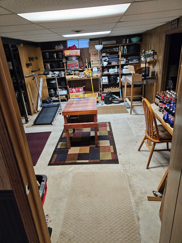 basement with a paneled ceiling and wood walls