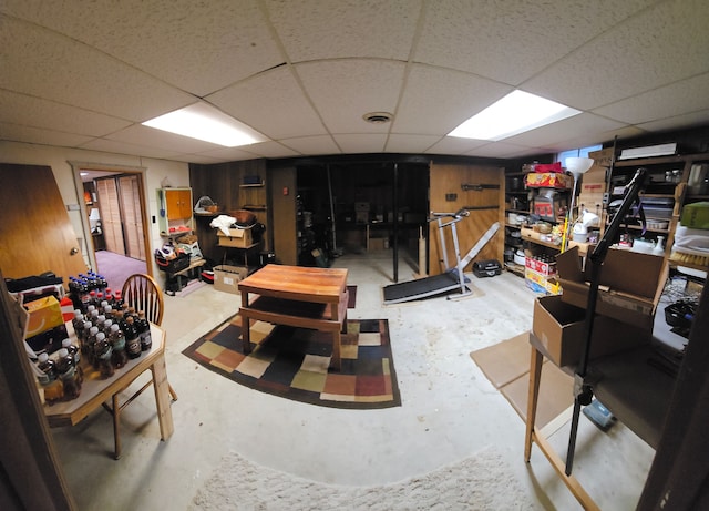 basement featuring a drop ceiling and wood walls