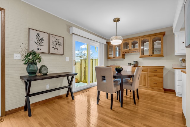 dining room with light hardwood / wood-style floors and brick wall