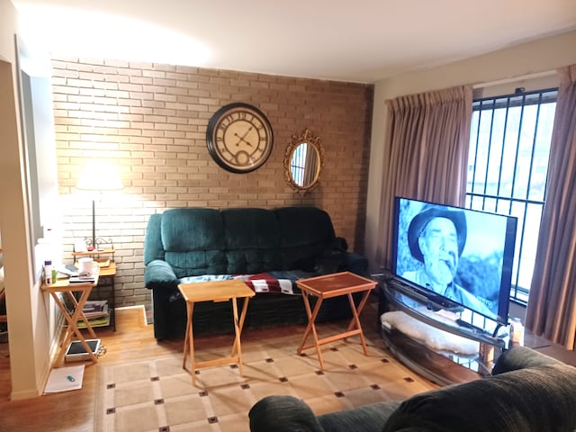 living room featuring light hardwood / wood-style flooring and brick wall