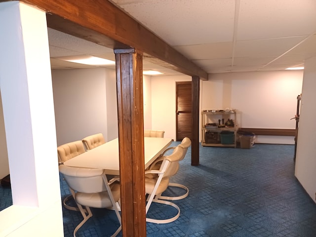 dining area featuring dark colored carpet and a drop ceiling