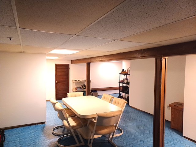 carpeted dining space with a paneled ceiling