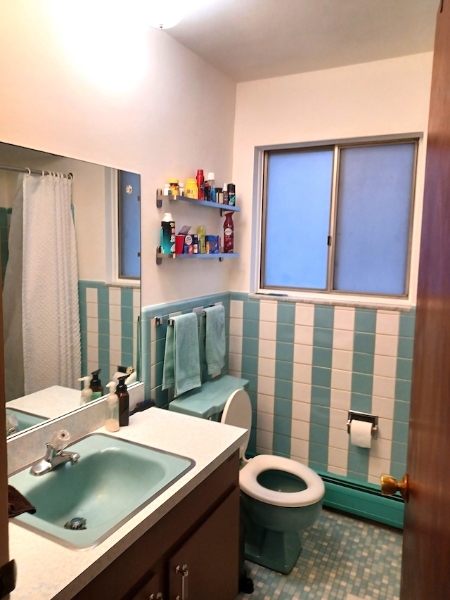 bathroom featuring baseboard heating, tile patterned floors, toilet, vanity, and tile walls