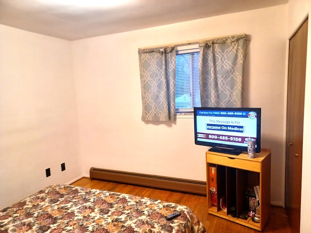 bedroom featuring hardwood / wood-style floors and a baseboard heating unit