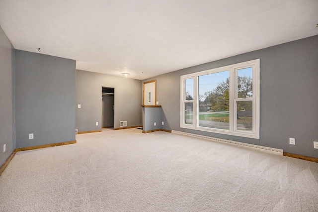 spare room featuring baseboard heating and light colored carpet