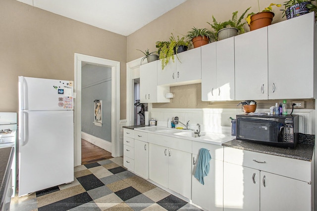 kitchen with sink, decorative backsplash, white cabinets, and white fridge