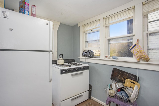 kitchen with white appliances and dark tile patterned flooring