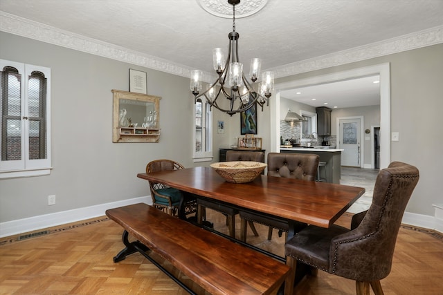 dining space featuring a textured ceiling, light parquet floors, a notable chandelier, and crown molding