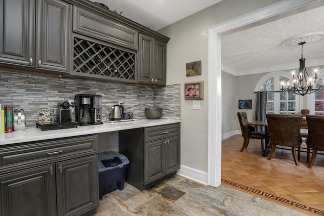 bar with decorative backsplash, crown molding, pendant lighting, an inviting chandelier, and light parquet flooring