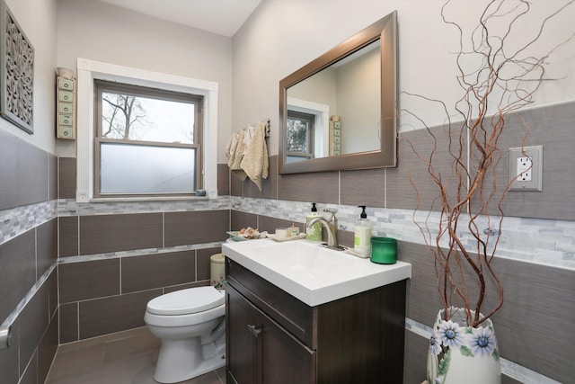 bathroom with tile patterned flooring, vanity, toilet, and tile walls