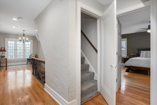 stairway with ceiling fan with notable chandelier and hardwood / wood-style flooring