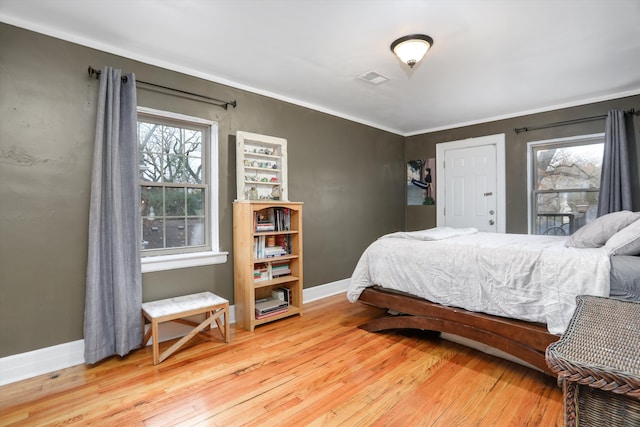 bedroom with ornamental molding and light wood-type flooring