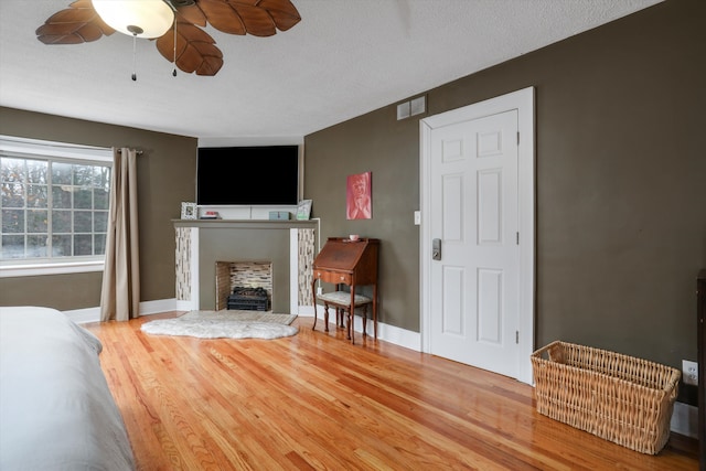 living room featuring hardwood / wood-style floors, ceiling fan, and a textured ceiling