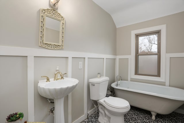 bathroom featuring a bathing tub, sink, tile patterned floors, lofted ceiling, and toilet