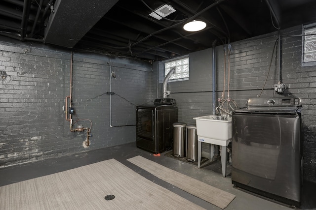 basement with washer and clothes dryer, brick wall, and sink