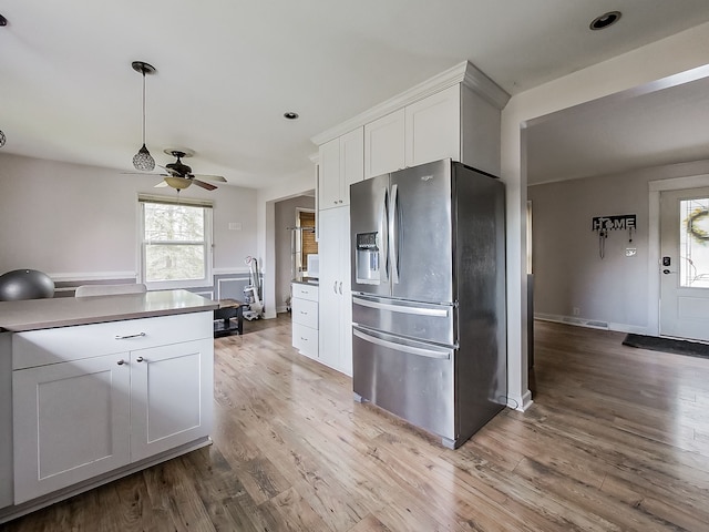 kitchen with white cabinets, stainless steel fridge with ice dispenser, light wood-type flooring, and ceiling fan