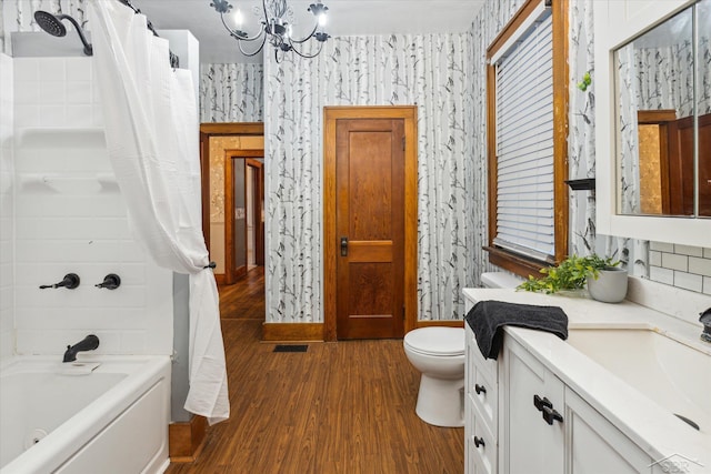 full bathroom featuring vanity, hardwood / wood-style flooring, an inviting chandelier, shower / bathtub combination with curtain, and toilet