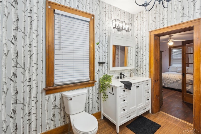 bathroom featuring hardwood / wood-style floors, vanity, toilet, and ceiling fan with notable chandelier