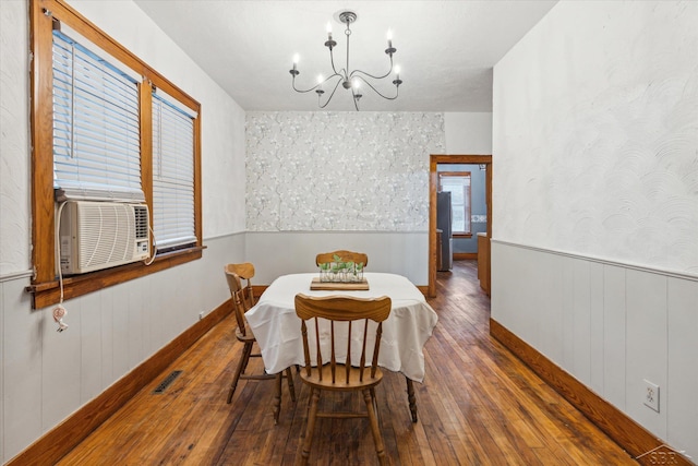 dining area featuring wood walls, cooling unit, dark wood-type flooring, and an inviting chandelier