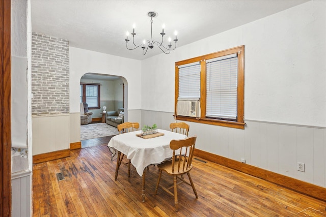 dining area featuring hardwood / wood-style flooring, cooling unit, and a chandelier