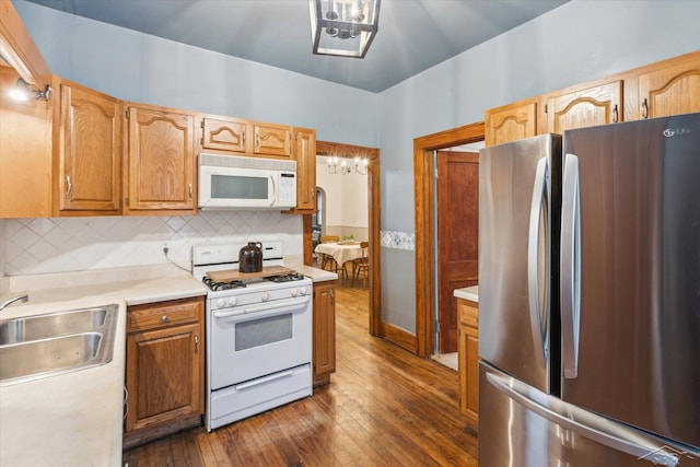 kitchen with decorative backsplash, dark hardwood / wood-style flooring, white appliances, and sink