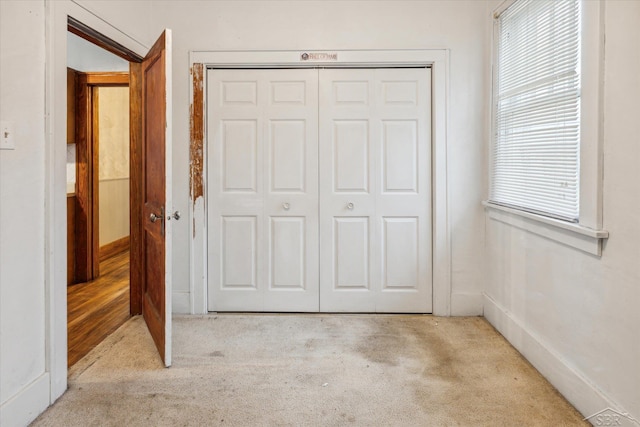 unfurnished bedroom featuring light colored carpet and a closet