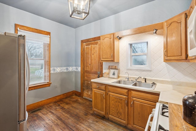 kitchen featuring sink, tasteful backsplash, dark hardwood / wood-style flooring, stainless steel fridge, and range