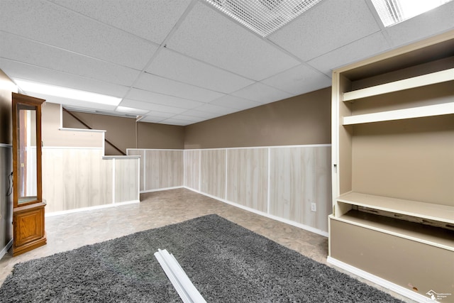 interior space with a paneled ceiling and wood walls