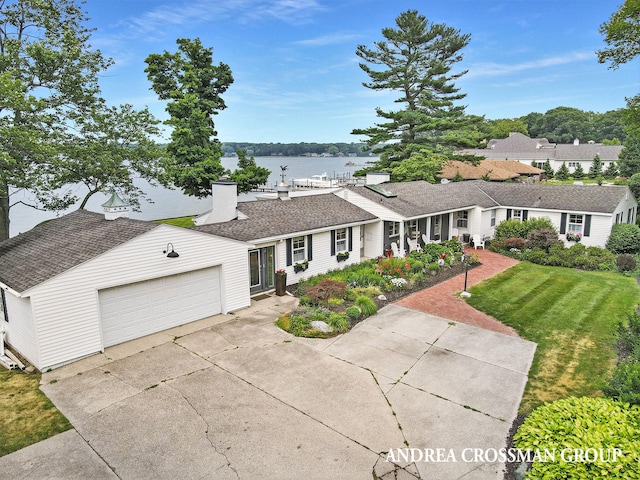 single story home featuring a front lawn, a water view, and a garage