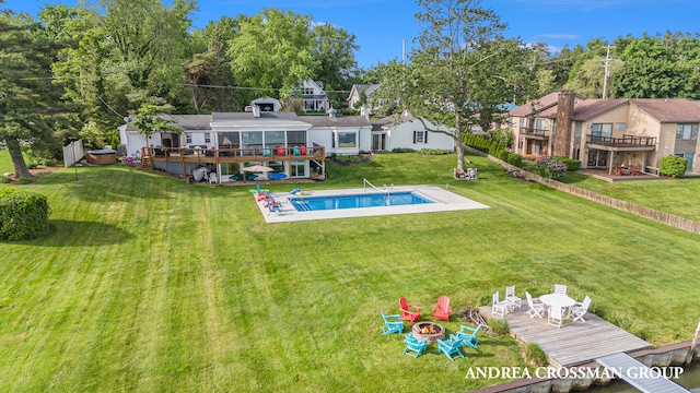 back of house featuring a lawn, a pool side deck, and a fire pit