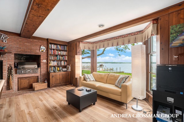 living room with beam ceiling, wooden walls, light hardwood / wood-style flooring, and a water view