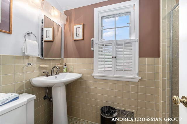 bathroom featuring toilet and tile walls