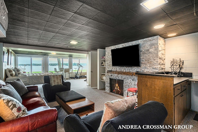 carpeted living room with a stone fireplace