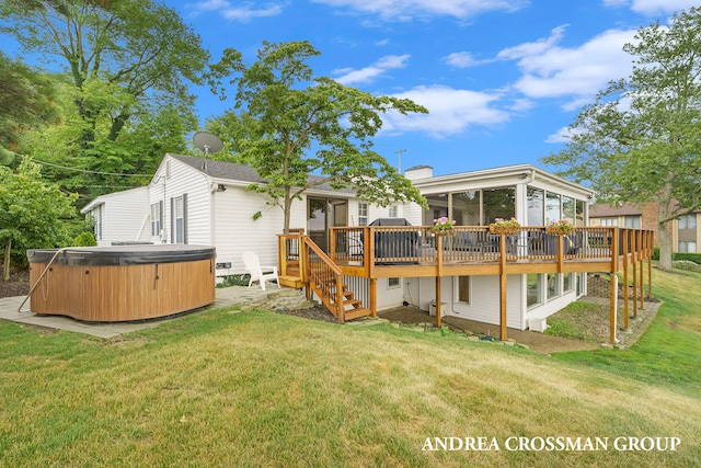 rear view of property featuring a sunroom, a deck, a yard, and a hot tub