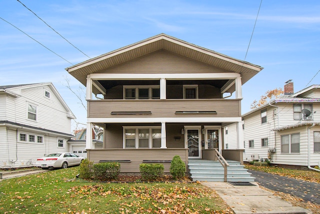 view of property with a balcony and a front lawn