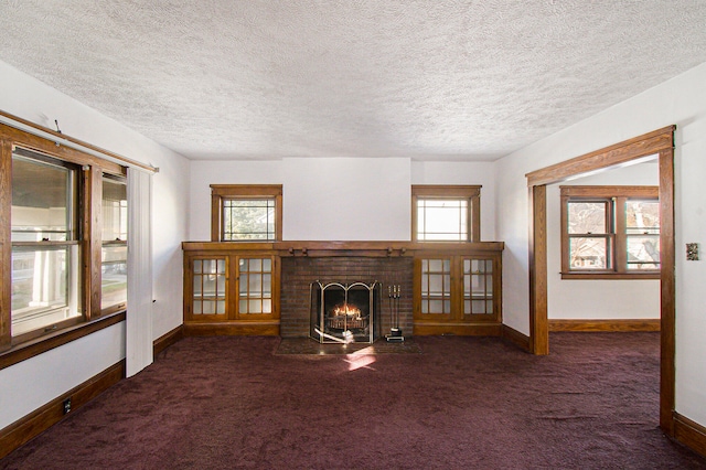 unfurnished living room featuring a textured ceiling, dark carpet, and a wealth of natural light