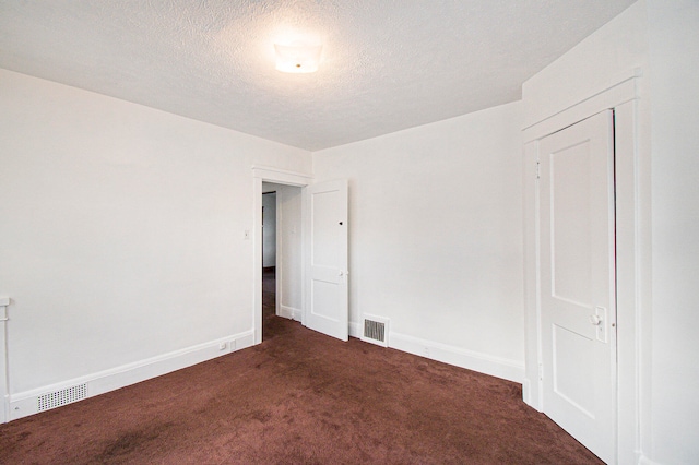 carpeted empty room featuring a textured ceiling