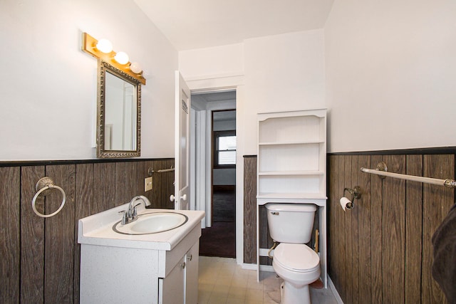 bathroom featuring vanity, toilet, and wood walls