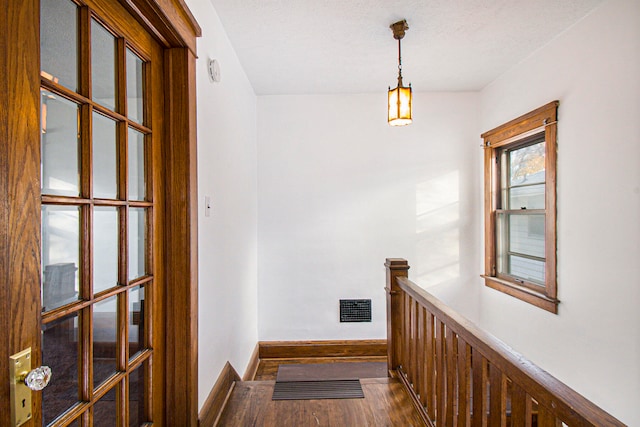 hall with a textured ceiling and dark wood-type flooring