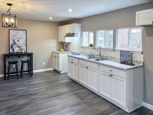 kitchen with backsplash, dark hardwood / wood-style floors, white cabinetry, and sink