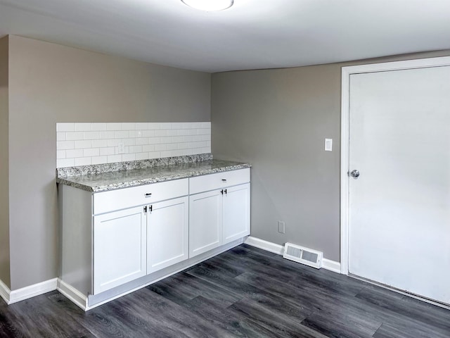 kitchen with backsplash, white cabinetry, and dark wood-type flooring